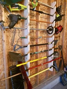 there are many different types of tools hanging on the wall in this room, including shovels and rakes