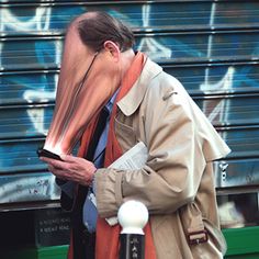 a man with his face covered by a large piece of art on the side of a bus