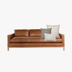 a brown leather couch with two pillows on it's back and one pillow in the middle