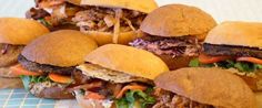 several pulled pork sandwiches are lined up on a blue and white checkered tablecloth