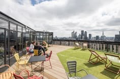 people are sitting at tables on the roof of a building with city in the background