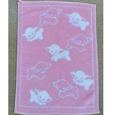 a pink and white towel with cartoon animals on it, sitting on a wooden surface