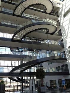 a spiral staircase in the middle of a large building with lots of windows on each floor