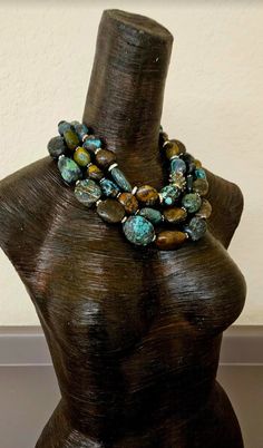 This multiple strand Hubei Turquoise boulder statement necklace has all the wow factor you have come to expect from Kat Kouture! This bold, chunky and heavy piece is actually a unisex design so men are welcome to it, also! Three strands of Hubei turquoise are space with either gold tone metal daisies or rhinestone rondelles. There is one inlaid turquoise brass bead from Tibet which serves as an accent and adds additional interest and drama. This piece adjusts from 17-20" and closes with an XL fa Hand-strung Multi-strand Turquoise Necklaces, Turquoise Multi-strand Gemstone Necklaces, Luxury Unique Multi-stone Turquoise Necklace, Rocker Chic Accessories, Luxury Multi-strand Turquoise Beaded Necklaces, Unique Blue Turquoise Multi-stone Necklace, Turquoise Statement Necklace, Gemstone Choker, Statement Bib Necklace