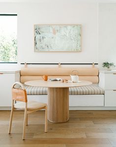 a table with two chairs and a painting on the wall above it in a white room