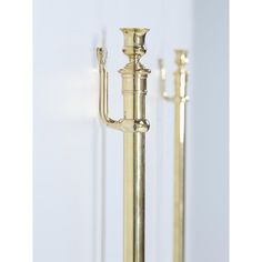 two brass candlesticks are standing next to each other on a white surface with one candle in the middle