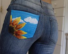 a woman's jeans with a sunflower painted on the back pocket and side pockets