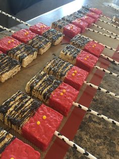 red, white and black desserts are lined up on a conveyor belt