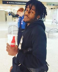 a man with dreadlocks holding a drink in an airport