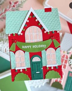 a hand holding up a card with a house on it and the words happy holidays