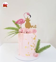 there is a pink cake with a flamingo on top and flowers in the bottom