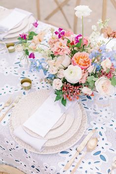 the table is set with flowers and place settings