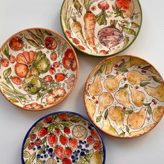 four bowls with fruits and vegetables painted on them