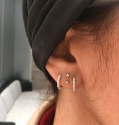 a person wearing a black hat and earring with three small white stones on it