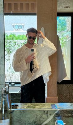 a man taking a selfie in front of a bathroom mirror with his cell phone