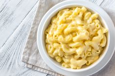 a white bowl filled with macaroni and cheese sitting on top of a napkin