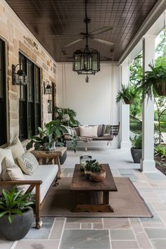 an outdoor living area with couches, tables and potted plants on the porch