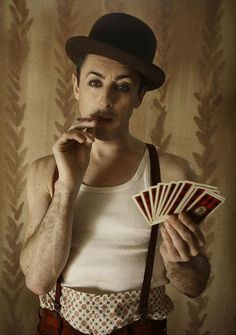 a man in top hat and suspenders holding cards