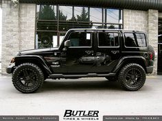 a black jeep is parked in front of a building with the words butler tires and wheels on it