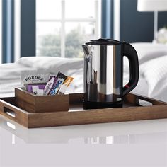 a wooden tray holding a coffee pot and some snacks