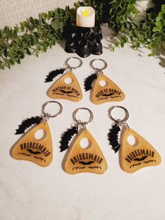 six wooden keychains with black and white logos are on a table next to some greenery