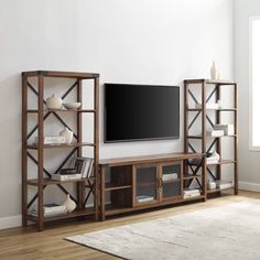 a living room with a large tv on top of a wooden entertainment center next to a window