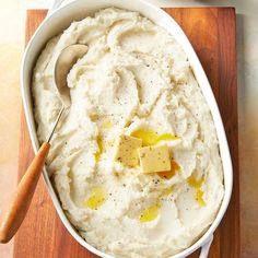 mashed potatoes with butter and seasoning in a white dish on a wooden cutting board