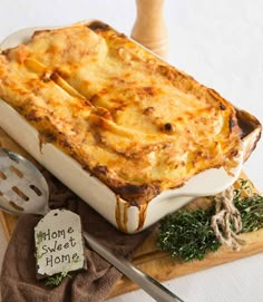 a casserole dish on a cutting board with utensils next to it