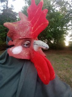 An original rooster mask made of wool for those who love transformation and fun. Unisex rooster mask. The mask is made from Latvian and merino wool with the addition of viscose and linen fibers and gauze. The mask is made using a flat template, after which it is given a three-dimensional 3D shape. The mask is made by wet felting wool with water and soap. On the mask I drew a rooster's face using wool and fibers. At the end of the work, I gave the mask the desired shape using natural gelatin. Thu Rooster Mask, Theatrical Mask, Festival Headdress, Animal Mask, Carnival Mask, Felting Wool, Halloween Mask, 3d Shape, Cosplay Halloween