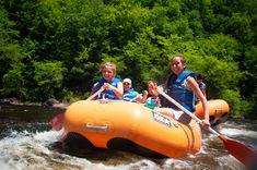 two girls are riding on an inflatable raft down a river with paddles