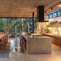 an open kitchen and dining room area with stone walls, concrete flooring and large windows