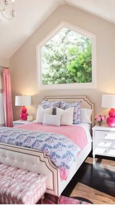 a bedroom with pink and white bedding, chandelier, windows, and rugs