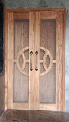 two wooden doors with glass panels on the front and back sides, in an empty room