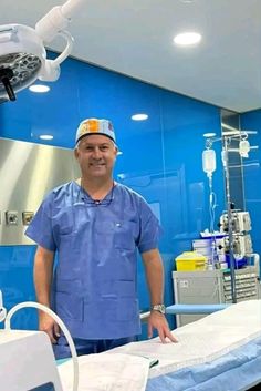 a man standing next to a hospital bed in a room with blue walls and lights