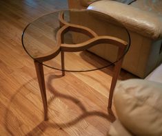 a glass table sitting on top of a hard wood floor next to a couch and chair