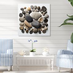 a living room with two chairs and a painting on the wall above them that has rocks in it