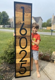 a young boy standing next to a wooden sign that reads 1, 600 on it