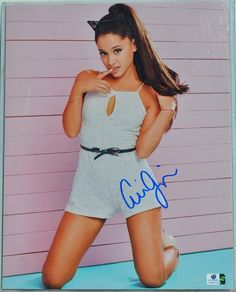 an autographed photo of a woman posing in front of a pink wall