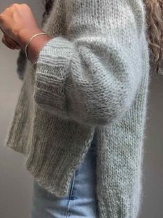 a close up of a person wearing a sweater and jeans with her hand on her hip