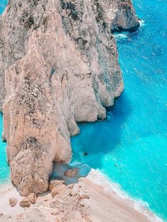 an aerial view of the blue water and rocky cliffs in the ocean, with one boat on it's side