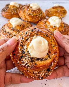 a person holding a pastry in their hands with cream cheese on top and sprinkles around it