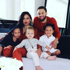 a man, woman and two children are sitting on a bed with a piano in the background