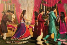 a group of people standing around each other in front of a stage with pink curtains