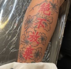 a person with a tattoo on their arm that has flowers and chinese characters written in red ink