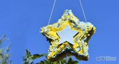 a yellow and white star shaped ornament hanging from a tree