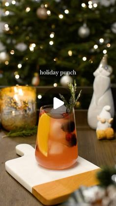 a holiday punch is sitting on a cutting board next to a christmas tree with lights in the background