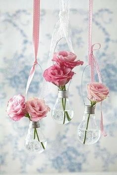 three vases filled with pink flowers hanging from strings