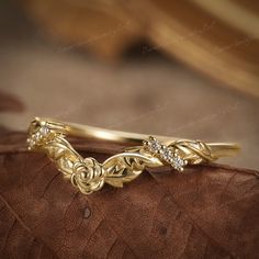 a close up of a gold ring on a brown leather surface with some diamonds in the middle