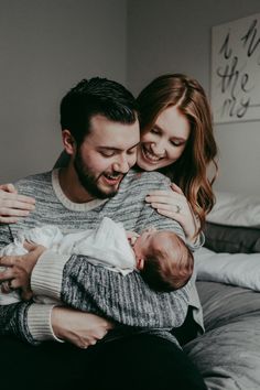 a man and woman holding a baby in their arms