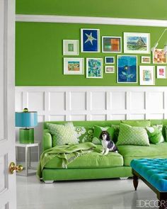 a living room filled with green furniture and pictures on the wall above it's headboard